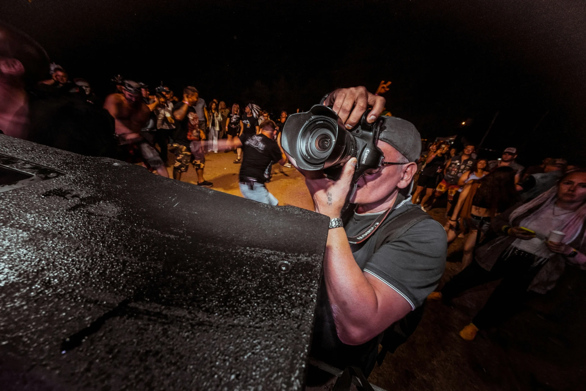 Un photographe en fosse capturant un artiste pendant un concert, dans des conditions de lumière complexes.