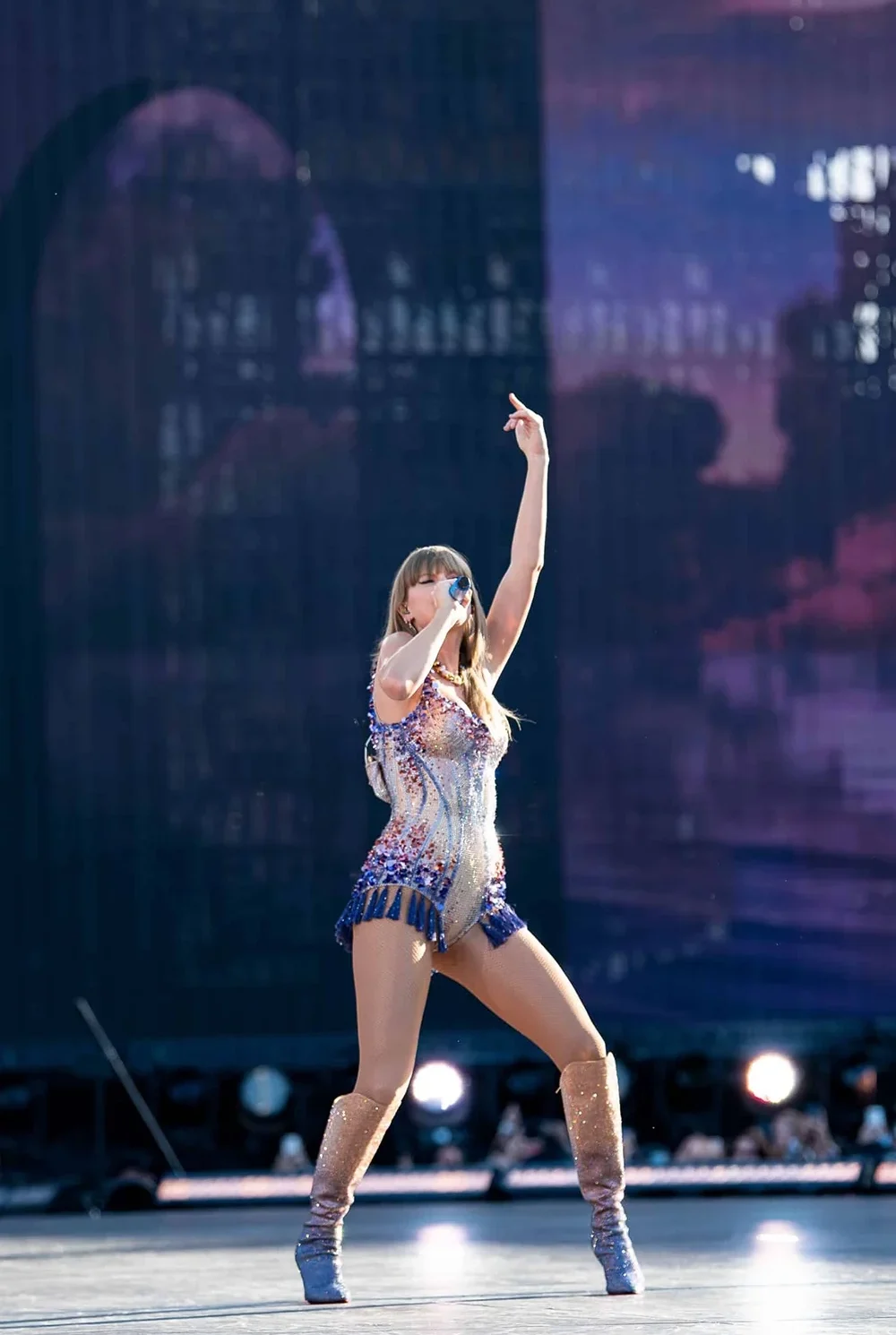 Taylor Swift levant la main en l’air, offrant un moment de connexion intense avec son public à Zurich lors de l’Eras Tour.