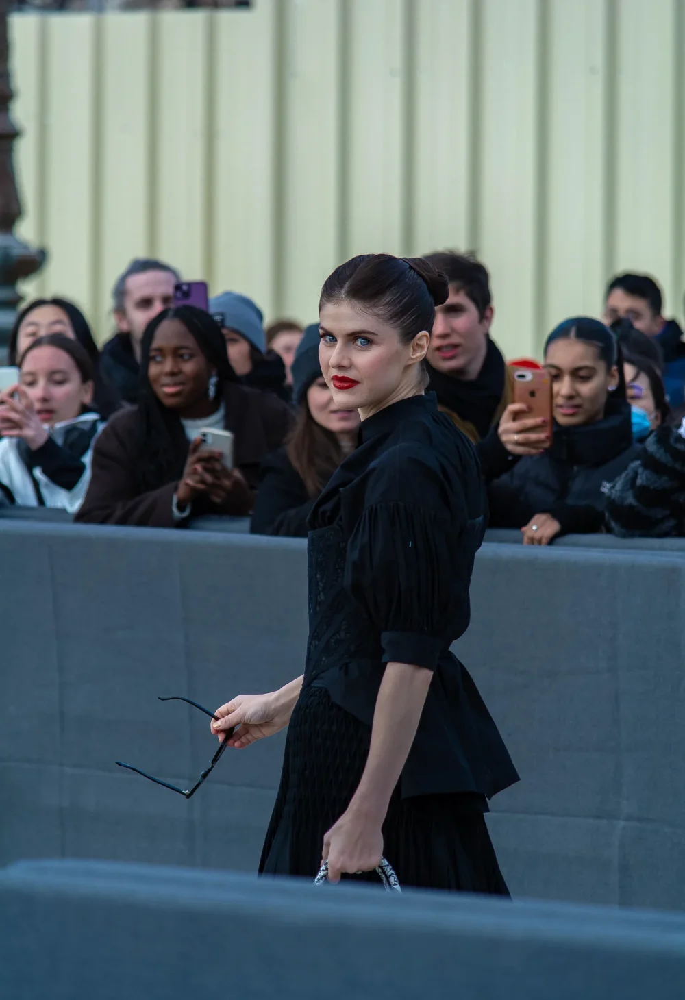 Alexandra Daddario avec chemise noire, corset décoré, maxi-jupe noire, escarpins noirs et sac Dior à la Fashion Week de Paris, Automne-Hiver 2023-2024, photo par Claudio Lavenia.