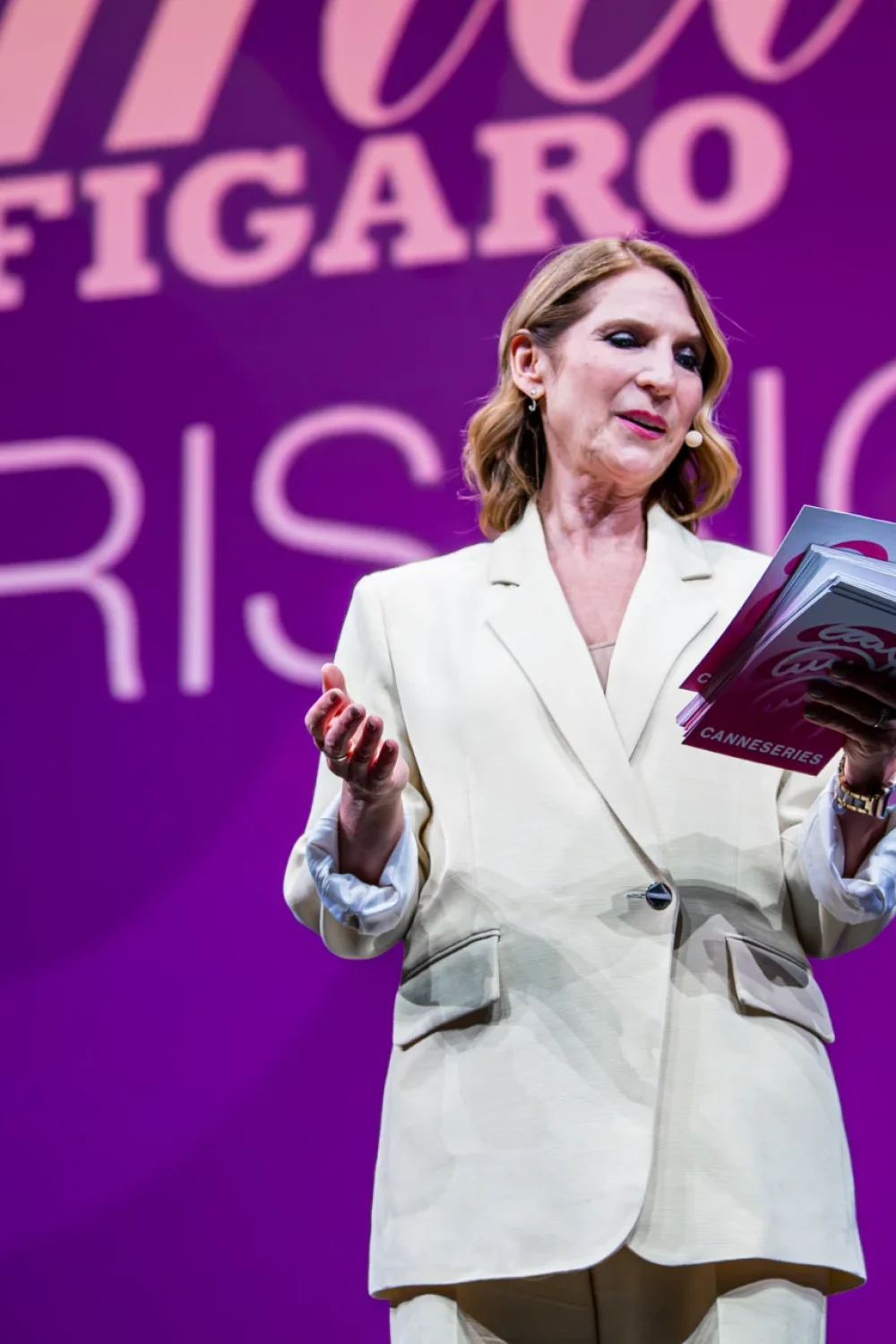 Femme en robe dorée s'exprimant lors d'un événement professionnel