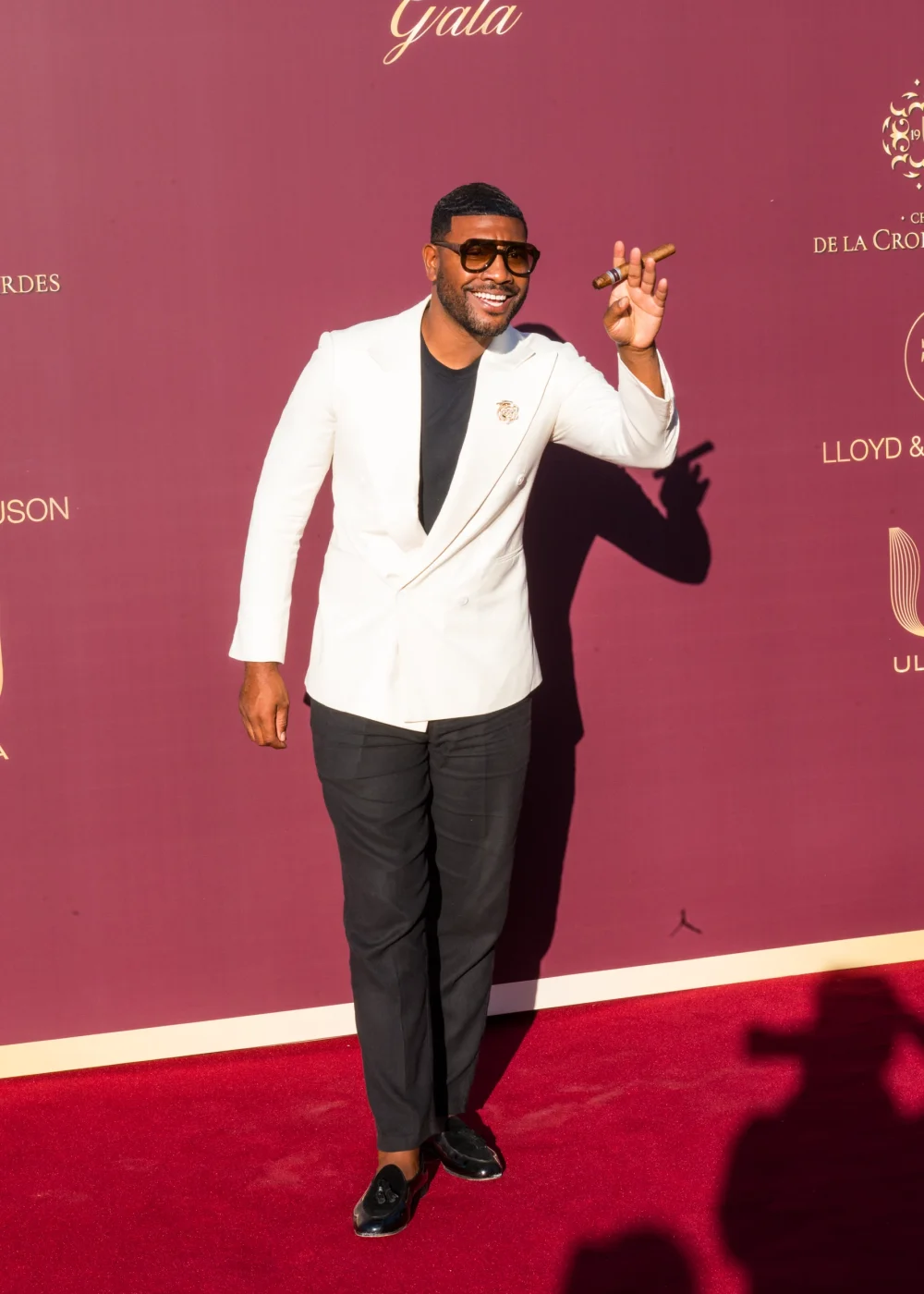 Homme en blazer blanc souriant sur tapis rouge lors d'un gala de prestige à Cannes