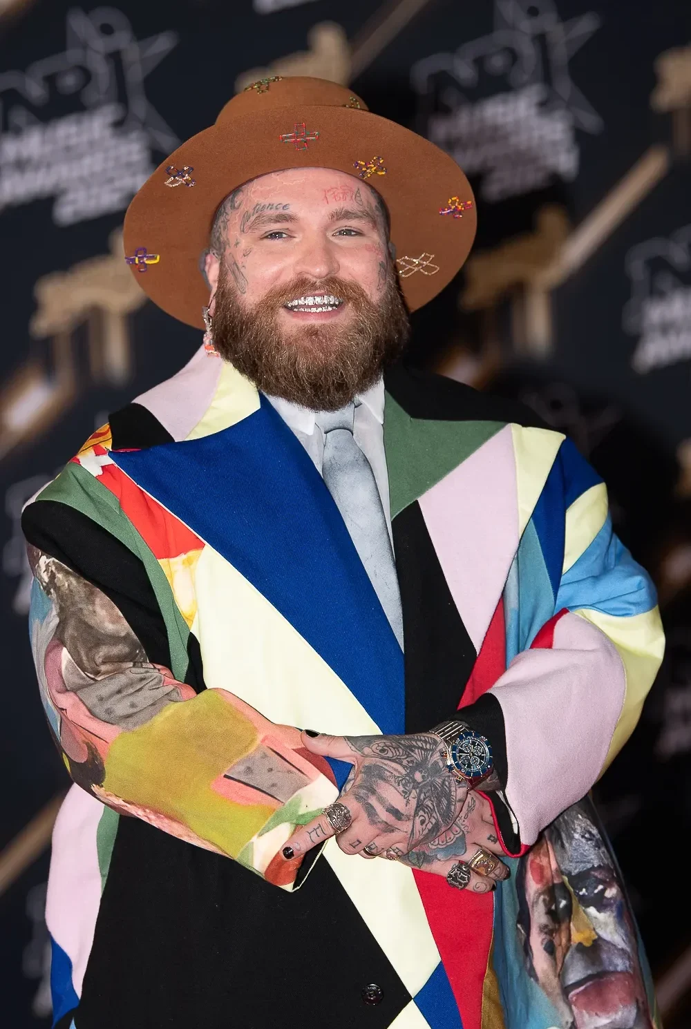 Teddy Smith pose sur le tapis rouge des NRJ Music Awards à Cannes, entouré de photographes.